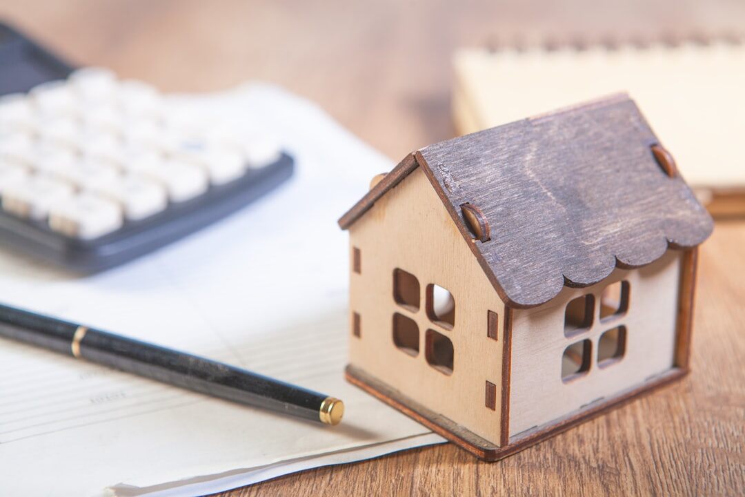Small house model placed next to estate planning documents and a pen